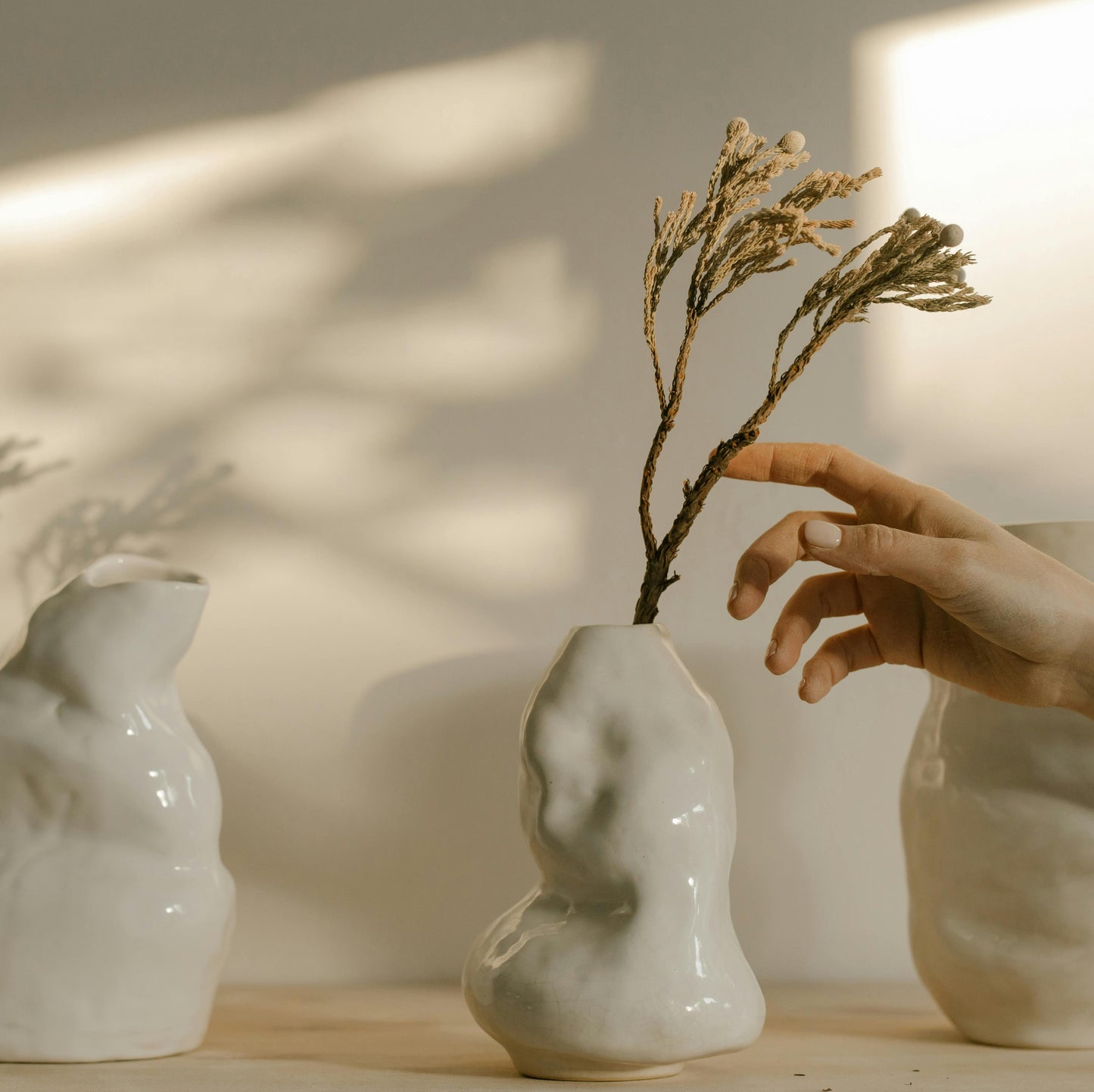 An abstract vase that that resembles an irregular stone with dried wheat in it.